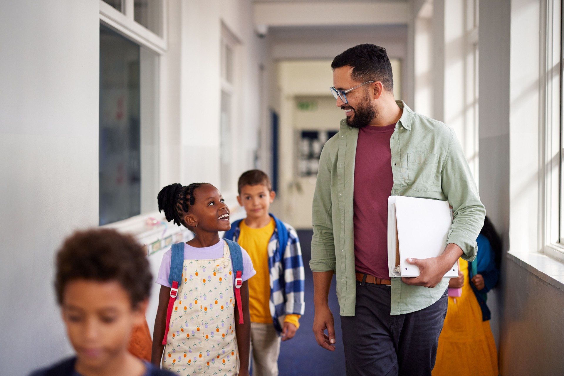 Teacher talking with little girl in primary school hallway