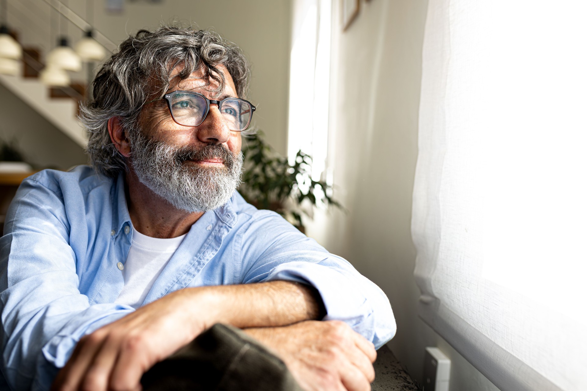 Senior man relaxing and looking out the window at home